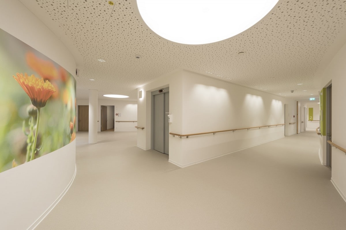 Helle, moderne Gänge mit großen Deckenlichtern und freundlichen Bilder prägen den Neubau des Seniorenwohnen am Föhrenpark in München