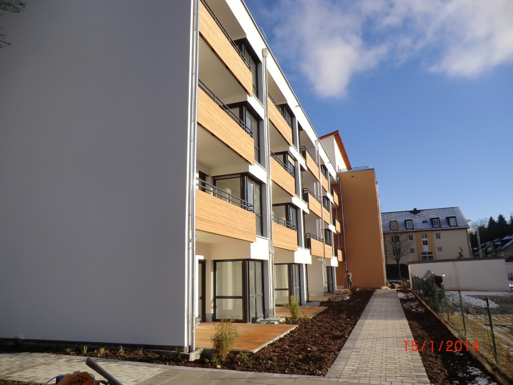 Holzverkleidete Balkone und helle Fassadenfarben lassen den Neubau des Service-Wohnen in Geretsried erstrahlen